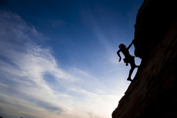 Rock climber clinging to a cliff. - obrazy, fototapety, plakaty