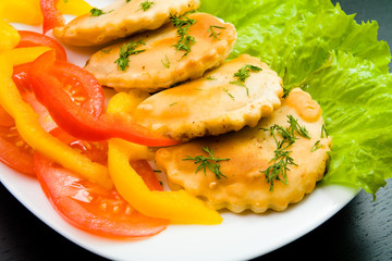 Closeup photo of plate with chebureks, salad, pepper and tomato