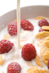 milk pouring onto muesli with raspberry isolated