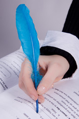 young woman hand holding a blue quill over an English notebook
