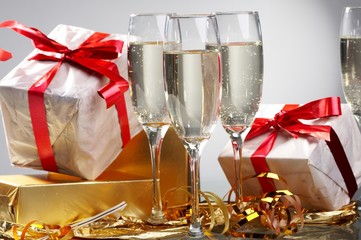 Glasses of champagne, gifts with red tapes and bows
