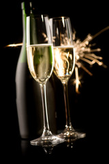 Zwei Sektgläser vor Flasche und Feuerwerk