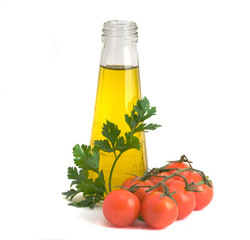Bottle of olive oil, tomatoes, and leaf of parsley ready for sal