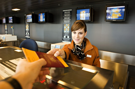 Female airline check-in attendant giving a passport and boarding pass to a passenger