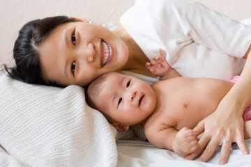 Obraz na płótnie Canvas Smiling mother lying wih her baby