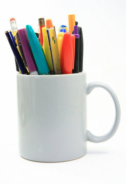 Rainbow of colored writing instruments in a coffee cup
