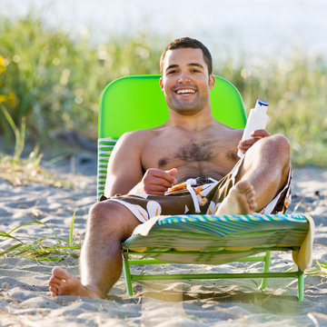 Man Applying Sunscreen Lotion At Beach