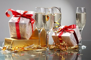 Glasses of champagne, gifts with red tapes and bows
