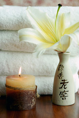 Candle, lily and white towels at spa
