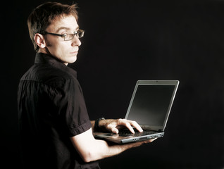 man on black background peers into computer