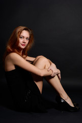 Fototapeta na wymiar .Beautiful redheaded girl posing in studio on dark background