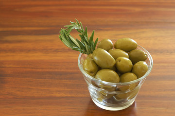 Single jar of green olives with rosemary