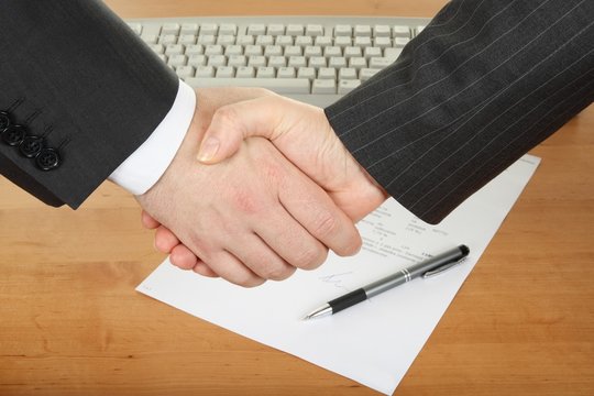 businessmens' handshake over contract and pen