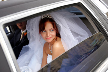 Smiling bride with groom in wedding limo