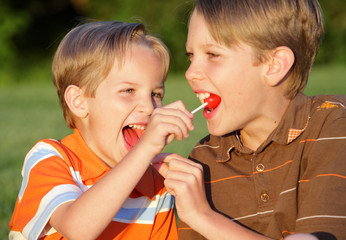 two brothers sharing lollipops