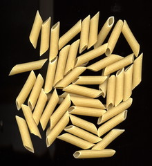 Pâtes, pasta. Penne sur fond noir.