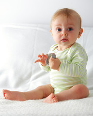 Bebe assis tiens dans ses mains un truc