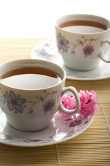 two cups of tea and flowers over bamboo mat isolated