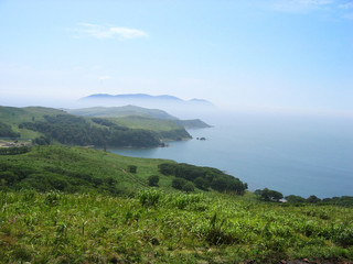 Blue bay in sunny day, distant island in the fog