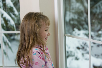 happy child looking out the window at snow