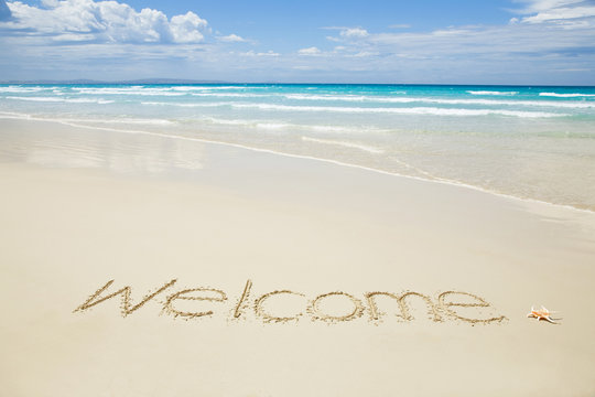 Welcome written on a tropical beach