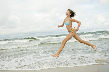 Fototapeta premium Young girl with starfish on the beach
