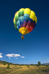 Globo aerostático sobre el cielo azul y pradera