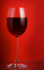 glass of red wine on red background
