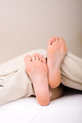 Fototapeta premium Woman's feet under the blanket