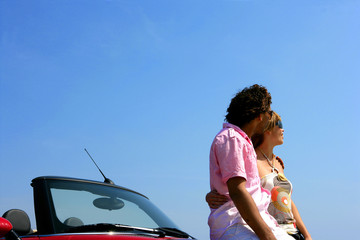 Jeune couple assis sur une voiture décapotable