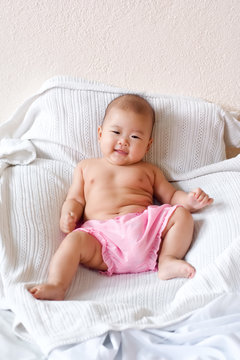Cute happy baby sitting up in bed