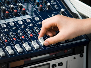 Human Hand using an audio mixer to tune the volume