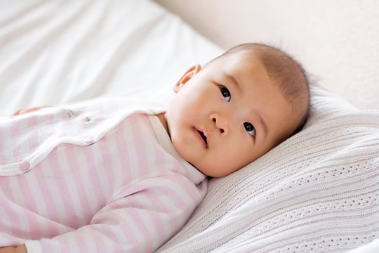 Baby lying in bed, curious expression on her face