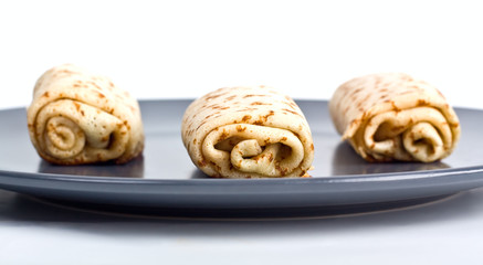 three pancake rolls shot from a low angle on a dark plate