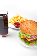 A hamburger, fries with ketchup and cola in a tall glass