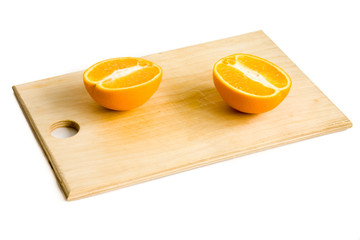 still life of two orange halves on wooden plate