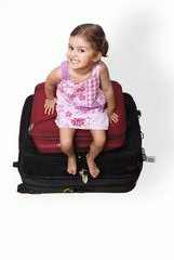 Cute little girl on top of a pile of suitcases