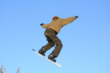 Fototapeta na wymiar Zdjęcie młodej męskiej snowboarder skoki na tle błękitnego nieba