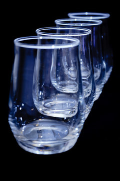 four empty glasses in a diagonal row on black - vertical