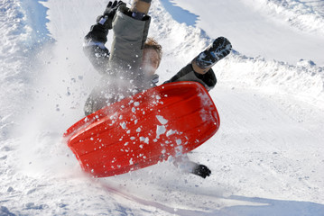 Boy in the Air with His Sled While Sledding Down the Hill