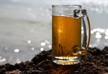 cold beer glass on a cliif, shiny sea background