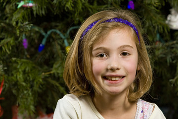 Happy child sitting in front of a Christmas tree