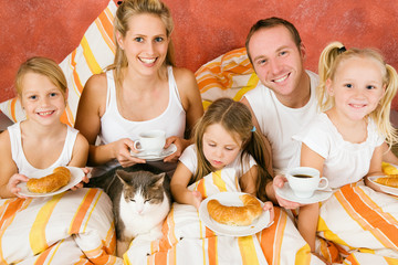 Familie samt Katze im Bett beim Frühstück