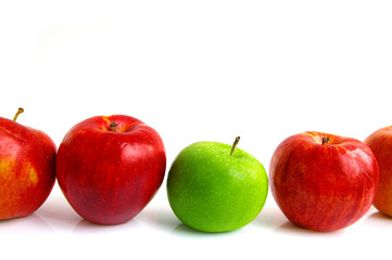 row of apples on white, one green apple