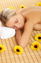 Obraz na płótnie Canvas Beautiful woman laying on bamboo mat during spa treatment