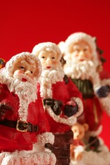 Three Santa Claus figurines over red background, studio