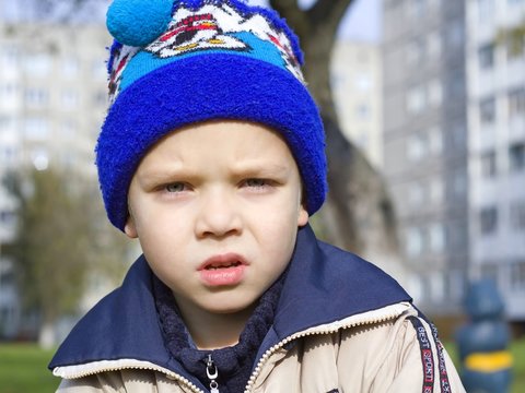 Portrait Of The Upset Child In A Dark Blue Cap