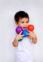 Cute little boy holding up colorful balls