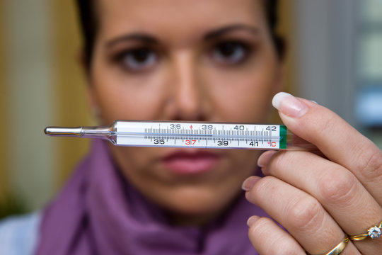 The sick woman with flu and fever thermometers