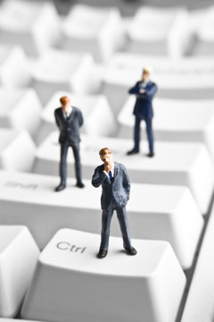 Businessman figurines placed on computer keyboard